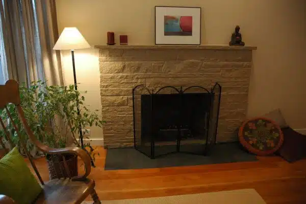 Zen style - painted stone fireplace makeover with flat black slate inlayed hearth, pillows, Buddha candleholder, original art, rocking chair, Ikea curtains, Seattle, Washington, USA