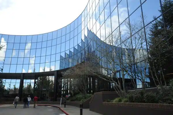 Technical workers head towards their black glass office building in Bellevue, Washington, USA on a bright sunny and cloudy day
