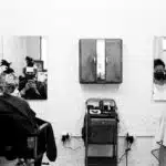 a black and white photo of a woman getting her hair cut
