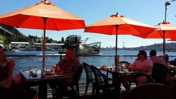 Watching the barges float by, outside deck, Ivars Salmon House, orange umbrellas for protection from the sun, Portage bay, Seattle, Washington, USA