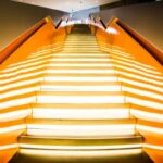 illuminated stairway with orange handrails