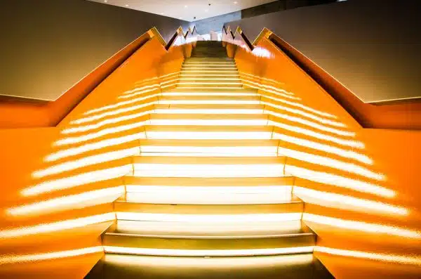 illuminated stairway with orange handrails