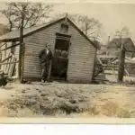 Male student leaning on a shed with chicken