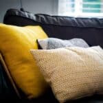 three assorted-color throw pillows on black sofa