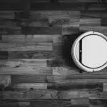 grayscale photo of round frame on wooden floor